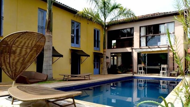 A pool area with lounge chairs and a dining table. - Pousada Santa Maria (Tiradentes)