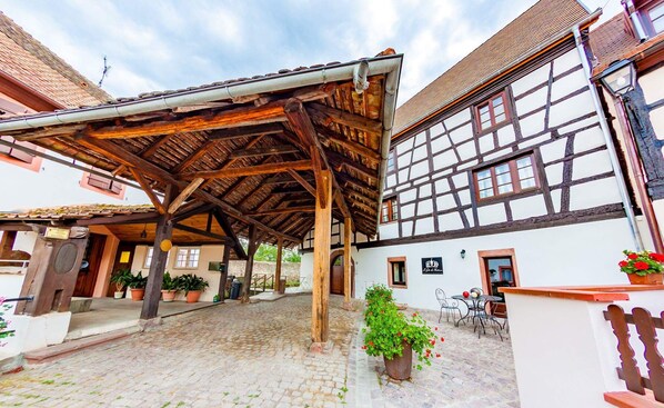 A traditional half-timbered building with a covered outdoor seating area and cobblestone flooring.