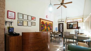 Un espace d’accueil avec un comptoir en bois, des certificats encadrés, une horloge et un tableau coloré.