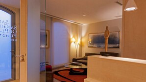 A modern hotel lobby with a glass partition, a sofa, a coffee table, and a painting on the wall. - San Gil Plaza Hotel (Zamora)