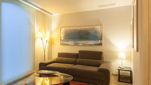 A modern living room with a sofa, a glass coffee table, and a painting on the wall. - San Gil Plaza Hotel (Zamora)