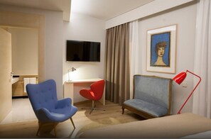 A hotel room with a bed, a desk, a chair, a TV, and a painting on the wall. - San Gil Plaza Hotel (Zamora)