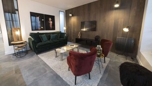 A modern living room with a green sofa, red armchairs, a coffee table, and a flat-screen TV mounted on the wall. - Heidi, 2BR/2BA, 6 people (París)