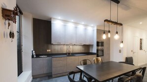 A modern kitchen with grey cabinets, a dark countertop, and a dining area with a table and chairs. - Heidi, 2BR/2BA, 6 people (París)