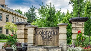 Schild für die Colorado State University mit einer Backsteinmauer und Blumenkästen.
