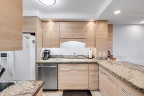 A modern kitchen with built-in appliances, a granite countertop, and wooden cabinetry.