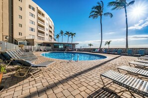 A pool area with lounge chairs and a building in the background.