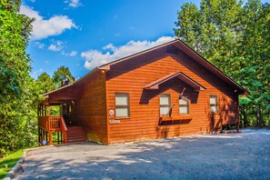 Eine Holzdiele mit Veranda und Treppe, umgeben von Bäumen.