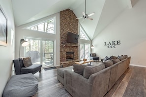Relax in this spacious living room with a stone fireplace, large window, and comfortable seating area.
