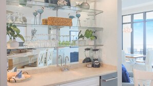 A kitchen with glass shelves displaying glassware, a blender, and a coffee maker.
