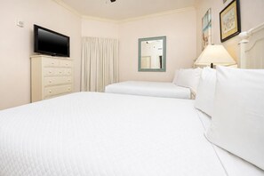 Una habitación de hotel con una cama, televisión, cómoda, espejo y lámpara.