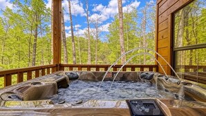 A hot tub with a wooden deck and a view of a forest. - A frame of Mind- 10 minutes to Dollywood!  Hot tub, Wifi, Free tickets! (Sevierville)