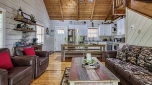 A cozy living room with a wooden ceiling, a coffee table, two sofas, and a kitchen area with cabinets and a refrigerator. - A frame of Mind- 10 minutes to Dollywood!  Hot tub, Wifi, Free tickets! (Sevierville)