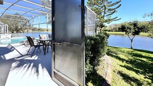 Un espace extérieur abrité comprenant une piscine, des chaises et une vue sur un lac.