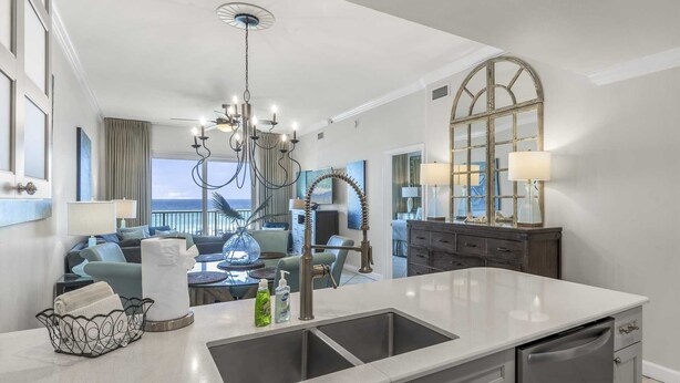 Une cuisine moderne dotée d’un grand îlot central, un coin repas offrant une vue dégagée et un salon avec un balcon donnant sur l’océan.