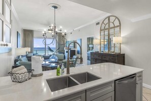 Una cocina moderna con una isla grande, un comedor con vistas y una sala de estar con balcón frente al océano.