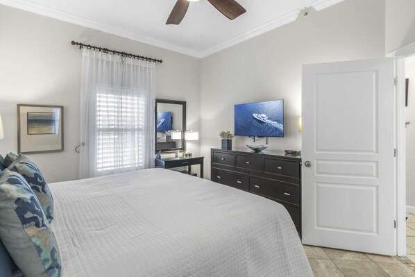 A bedroom with a bed, a dresser, a television, and a door.