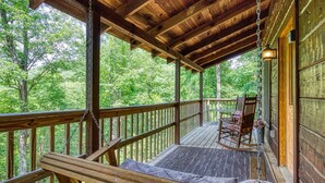 A wooden deck with a rocking chair and a bench, overlooking a forested area. - Pooh Bear, Hot Tub, WIFI, $560 FREE tickets each paid day!!! (Sevierville)