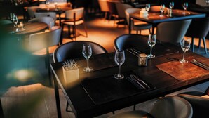 Ein Restaurant mit gedeckten Tischen, jeweils mit Weingläsern und Besteck.