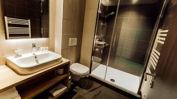 Ein modernes Badezimmer mit einem großen Waschbecken, Toilette und einer Duschkabine aus Glas.