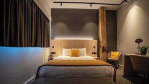 Ein modernes Hotelzimmer mit einem großen Bett, einem Schreibtisch und einem Sessel.