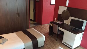 Habitación de hotel con dos camas, un escritorio, un televisor y un armario.