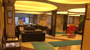 Un vestíbulo de hotel con zonas de estar, una recepción y una pared con un mural decorativo.
