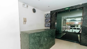 Un área de recepción con mostrador de mármol, un reloj y varias fotografías enmarcadas en la pared.