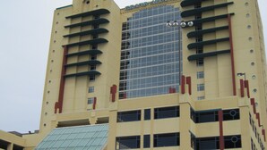 A multi-story hotel with a prominent glass facade and a parking garage entrance. - Stunning 3 BR, 3 Bath Grand Atlantic Direct Oceanfront (Myrtle Beach)
