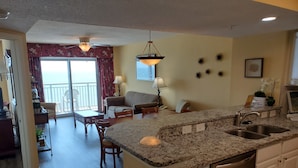A modern kitchen with granite countertops, a built-in dishwasher, and a dining area with a table and chairs. - Stunning 3 BR, 3 Bath Grand Atlantic Direct Oceanfront (Myrtle Beach)