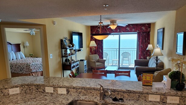 A kitchen with granite countertops, a double sink, and a dining area with a table and chairs. - Stunning 3 BR, 3 Bath Grand Atlantic Direct Oceanfront (Myrtle Beach)