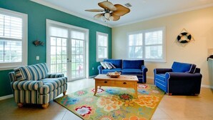 A living room with a striped sofa, a blue sofa, a coffee table, and a ceiling fan. - Summer Wind- An island getaway in the perfect location. (Holmes Beach)