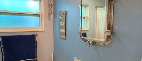 Un baño con un lavamanos blanco, un espejo y una toalla colgada en la pared.