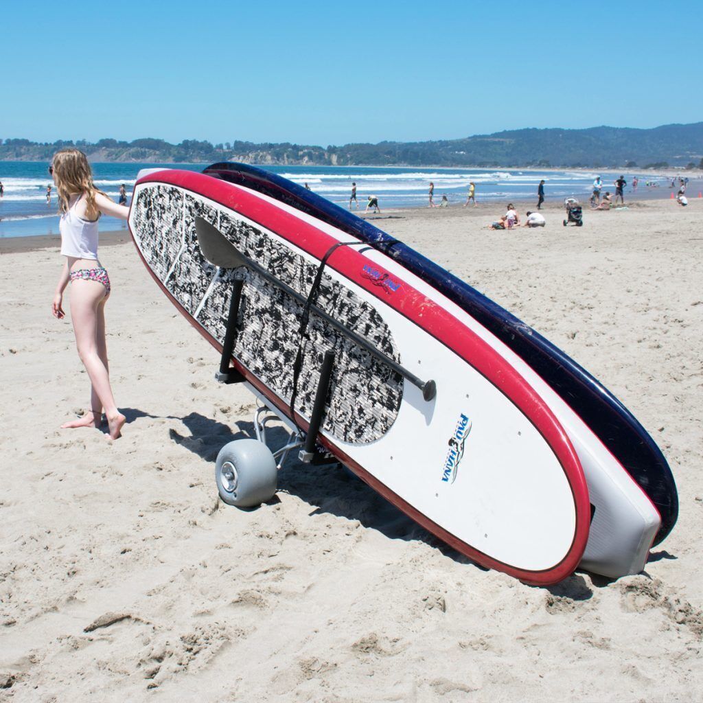 A beach scene with a surfboard on a cart.