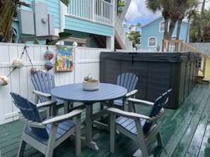 A covered patio with a round table and four chairs, surrounded by a white fence with decorative elements. - Beach View, Private Plunge Pool, Charming 1938 Bungalow Madeira Beach Gulf-Blvd (Madeira Beach)