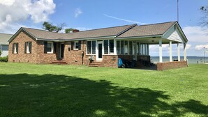 A brick house with a covered porch and a view of the water.