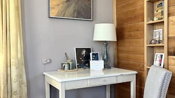 Une pièce avec un bureau blanc, une chaise grise, une bibliothèque en bois et un tableau accroché au mur.