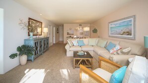 A spacious living room with a large sectional sofa, a coffee table, and a dining area with a blue cabinet. - Kingston Arms Paradise!
 Saint  Armands Circle & Lido Beach!  Fully Equipped! (Sarasota)