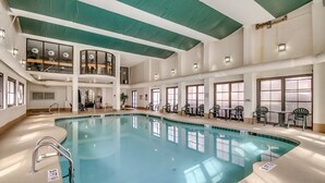 An indoor swimming pool with a clear view of the pool area, multiple seating areas, and a high ceiling with green and white panels. - 3BR Direct Oceanfront Condo in the Palms (Myrtle Beach)