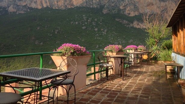 Una terrazza con tavoli e sedie, con vista su un paesaggio montuoso.