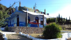 Una casa a due piani con fondamenta in pietra, un'amaca e un muro di pietra che circonda la proprietà.