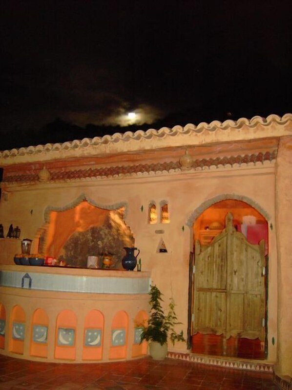Un edificio tradicional con un vestíbulo de azulejos, una pared de piedra y una puerta de madera.