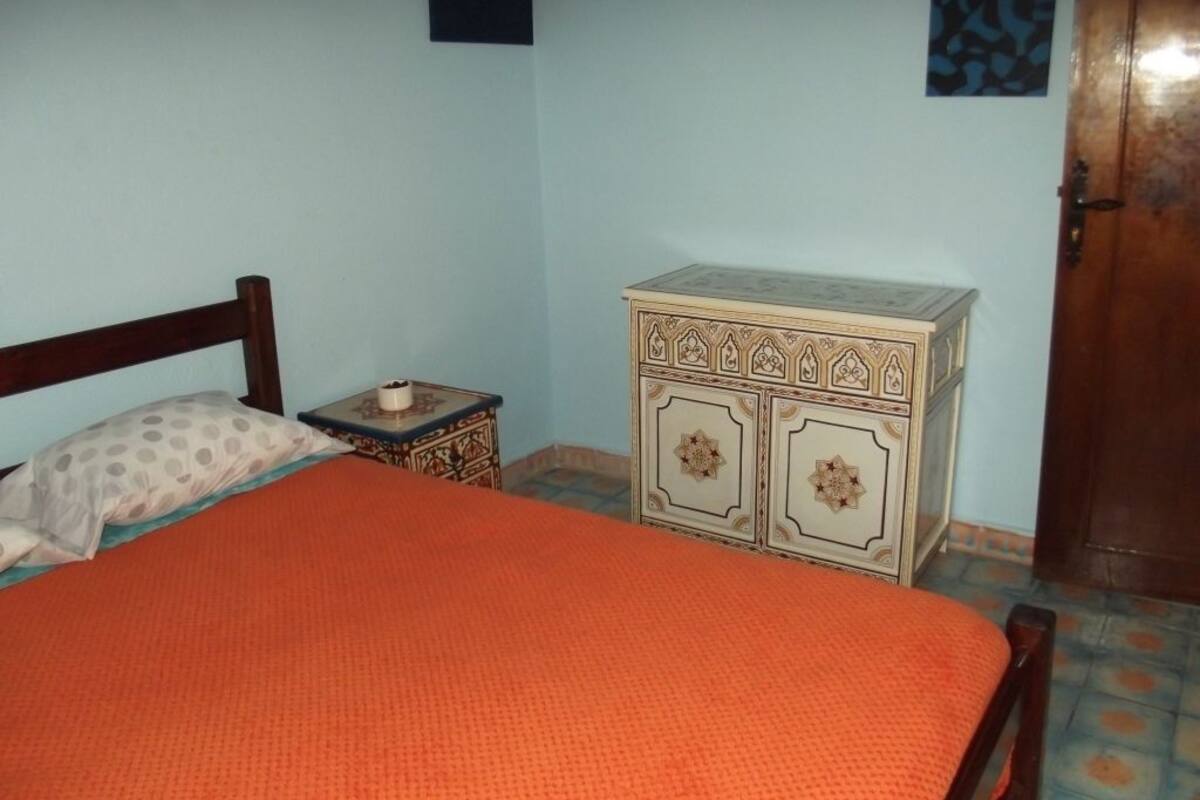A bedroom with a bed, a dresser, and a door.