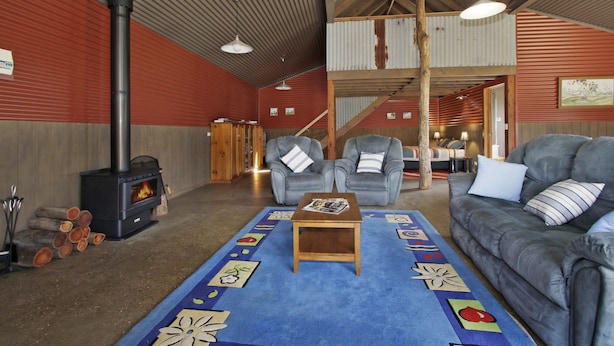 A cozy interior with a fireplace, two armchairs, a sofa, and a patterned rug. - Studio @ Quins Gap Retreat (Bright)