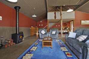 A cozy interior with a fireplace, two armchairs, a sofa, and a patterned rug. - Studio @ Quins Gap Retreat (Bright)