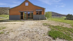 A single-story wooden building with a gabled roof, large sliding glass doors, and a small window. - Studio @ Quins Gap Retreat (Bright)