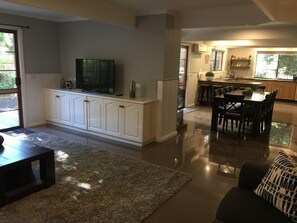 A modern kitchen with white cabinets, a dining area with a table and chairs, and a living room with a sofa and a coffee table. - Tudor House - Large Family Home (Bright)