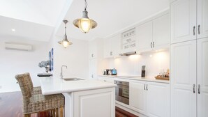 Una cocina moderna con armarios blancos, una isla central e iluminación colgante.