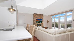 Una cocina moderna con chimenea de piedra, muebles blancos y un amplio ventanal con vistas.