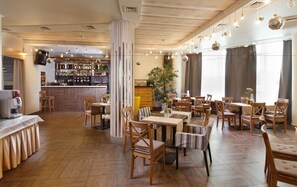 Un restaurante con suelos de madera, sillas a rayas y una zona de bar con estanterías llenas de botellas.